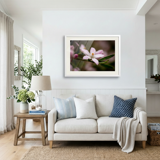 Living room with a beige sofa, decorative pillows, and a framed flower picture on the wall.