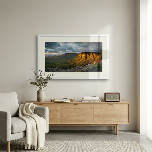 Living room with a landscape painting on the wall, a wooden sideboard, and a chair with a blanket.