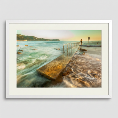 Person standing in Newport ocean pool at sunrise, Northern Beaches Sydney with soft golden light and calm water white Frame
