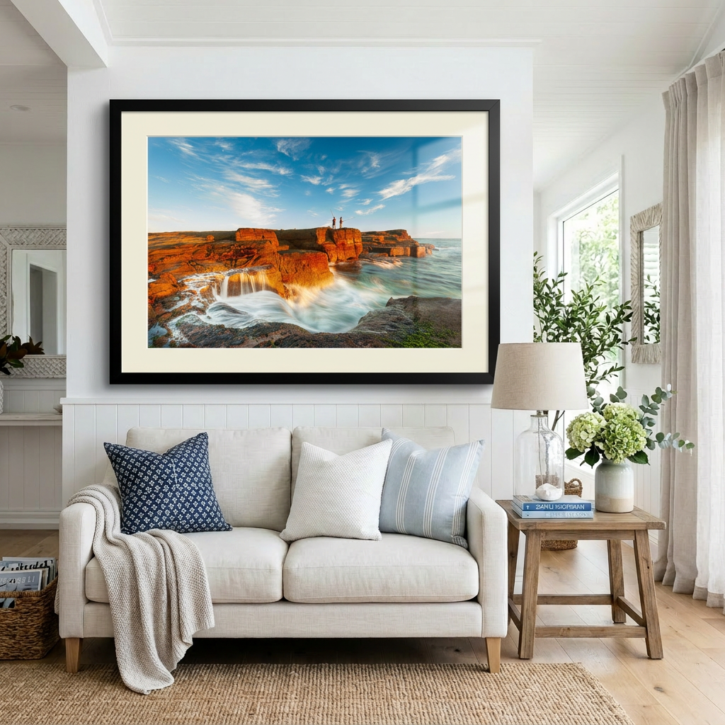 A landscape photograph featuring two figures fishing from a cliff edge with a vibrant sunset in the background, over a body of water. Norah Head lighthouse, NSW coast — fine art coastal wall art