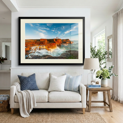 A landscape photograph featuring two figures fishing from a cliff edge with a vibrant sunset in the background, over a body of water. Norah Head lighthouse, NSW coast — fine art coastal wall art