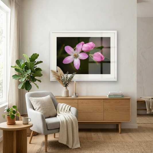 Living room with a gray armchair, wooden sideboard, and framed pink flower print on the wall.