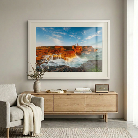 A landscape photograph featuring two figures fishing from a cliff edge with a vibrant sunset in the background, over a body of water. Norah Head lighthouse, NSW coast — fine art coastal wall art